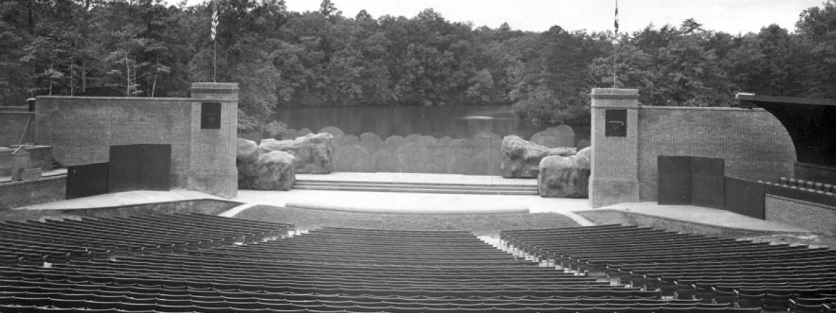 Outdoor amphitheatre with rows of seats separated by two aisles overlooking Lake Matoaka