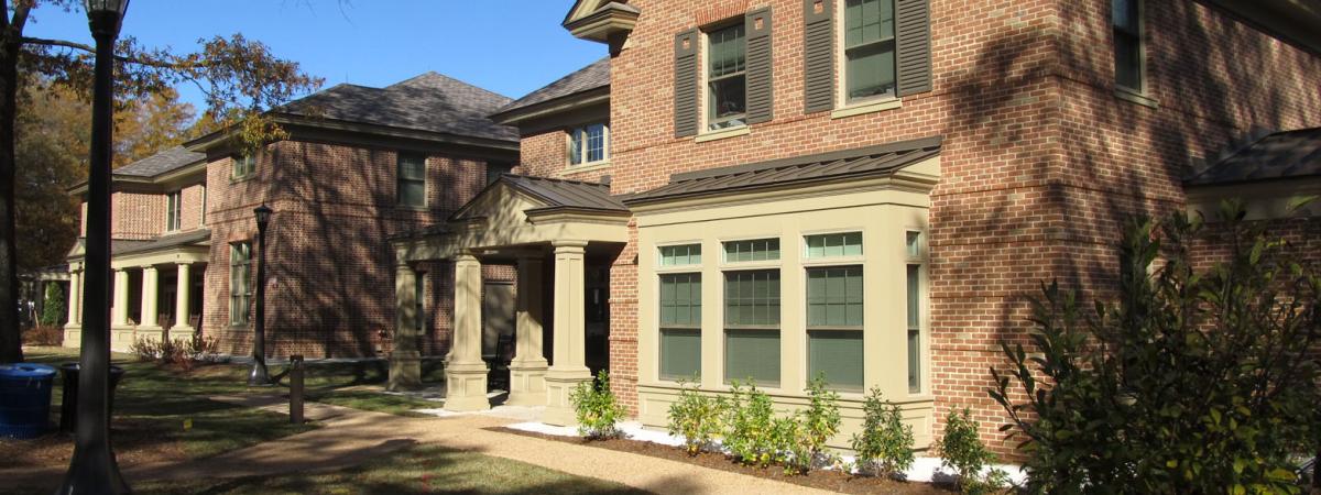 Two story brick house with covered porch with columns, and bay windows