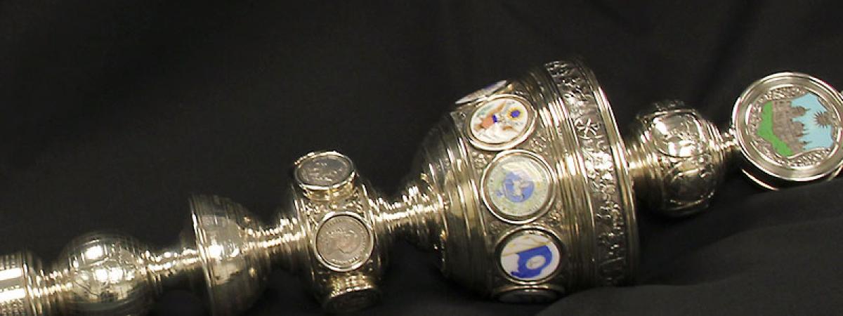 Silver mace with eagle on top, a round version of the college seal, and several other smaller round seals