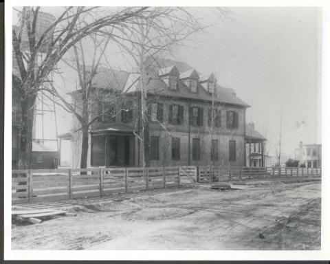 Black and white photos of the original Taliaferro hall with wood fencing and an unpaved road in front