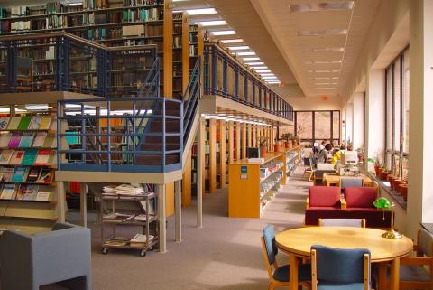 Interior of Hargis Library with study desks lit by large windows facing the bay, and an open staircase to the stacks