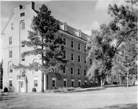 Five story birck dormitory surrounded by trees