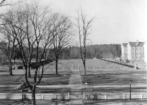 Black and white photo of the Sunken Garden with white picket fence in front and Blair Hall in the distance