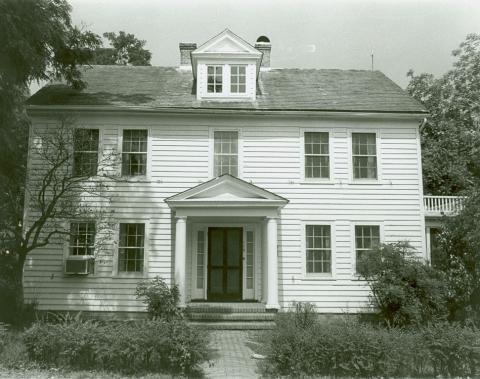 Two story white house with covered entrance and dormer window