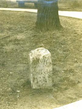 Rectangular, domed stone with the cypher and college name carved into it