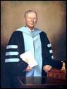 Standing portrait of David Paschall in black and light blue regalia