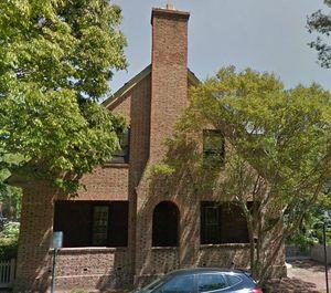 Front facade of two story brick house with porch and chimney