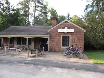 Single story brick lodge with outdoor seating and sign with a cup of coffee