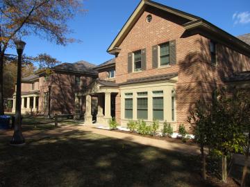 Two story brick house with covered porch with columns, and bay windows