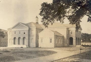 Black and white photo of Ewell Hall with three tall brick arches at the entry