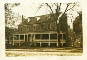 Three story house with dormer windows and a wrap around covered porch