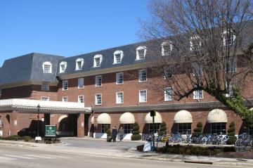 Three story brick building with covered entrance, round awnings on the first floor windows, and bike racks