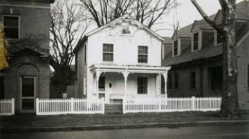 Simple two story white house with covered porch and picket fence