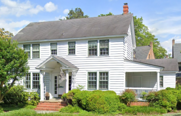 Two story white house with covered front entry and porch on the side