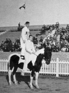 Two students, one sitting and the other standing, on the back of a horse