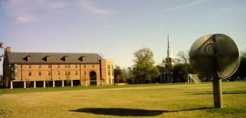 Wide open green field with dormitory in the background