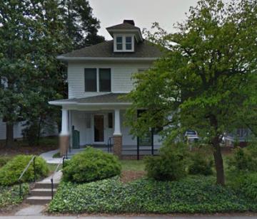 Two story white house with covered porch and roof dormer